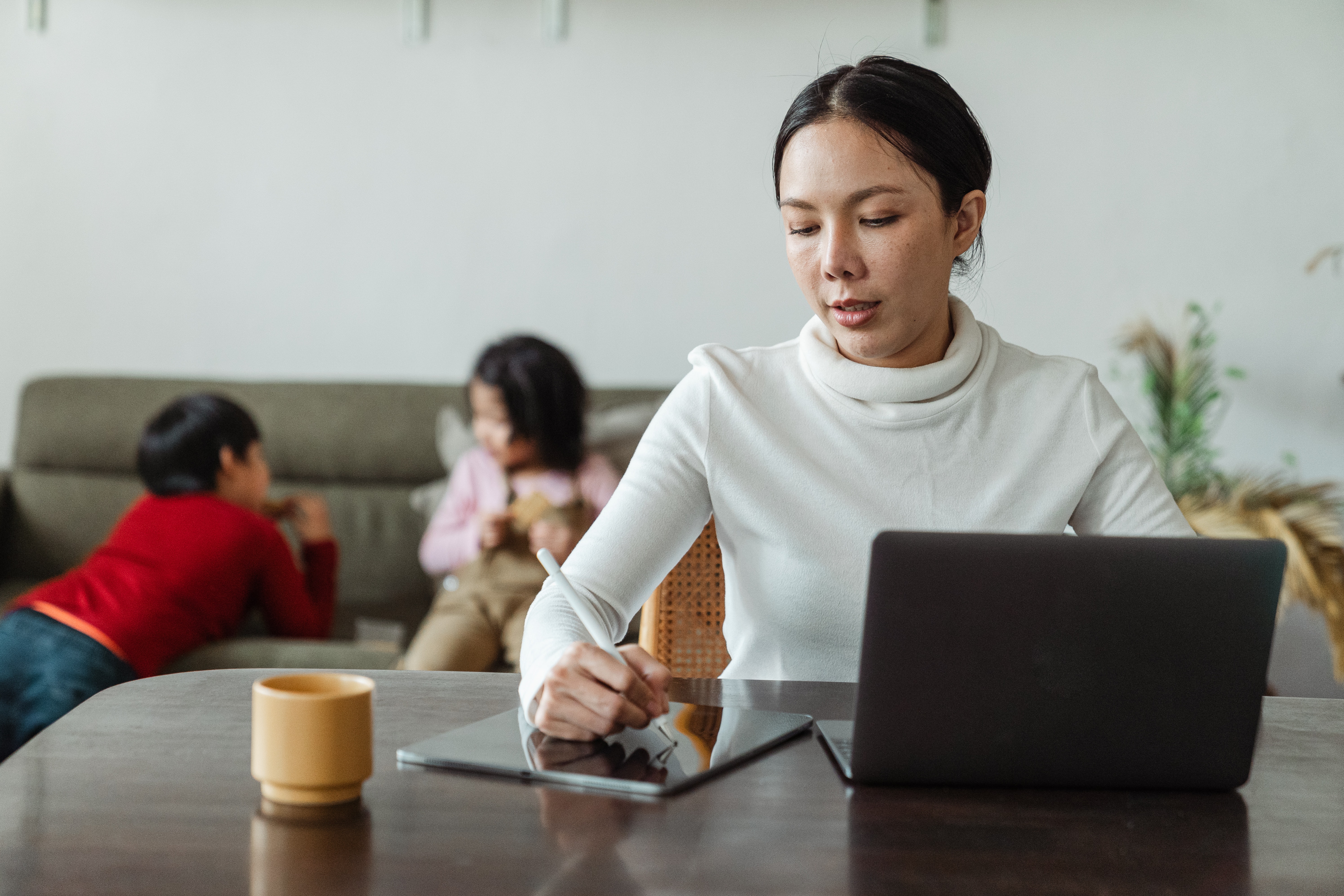 mother working at computer with two young children in background